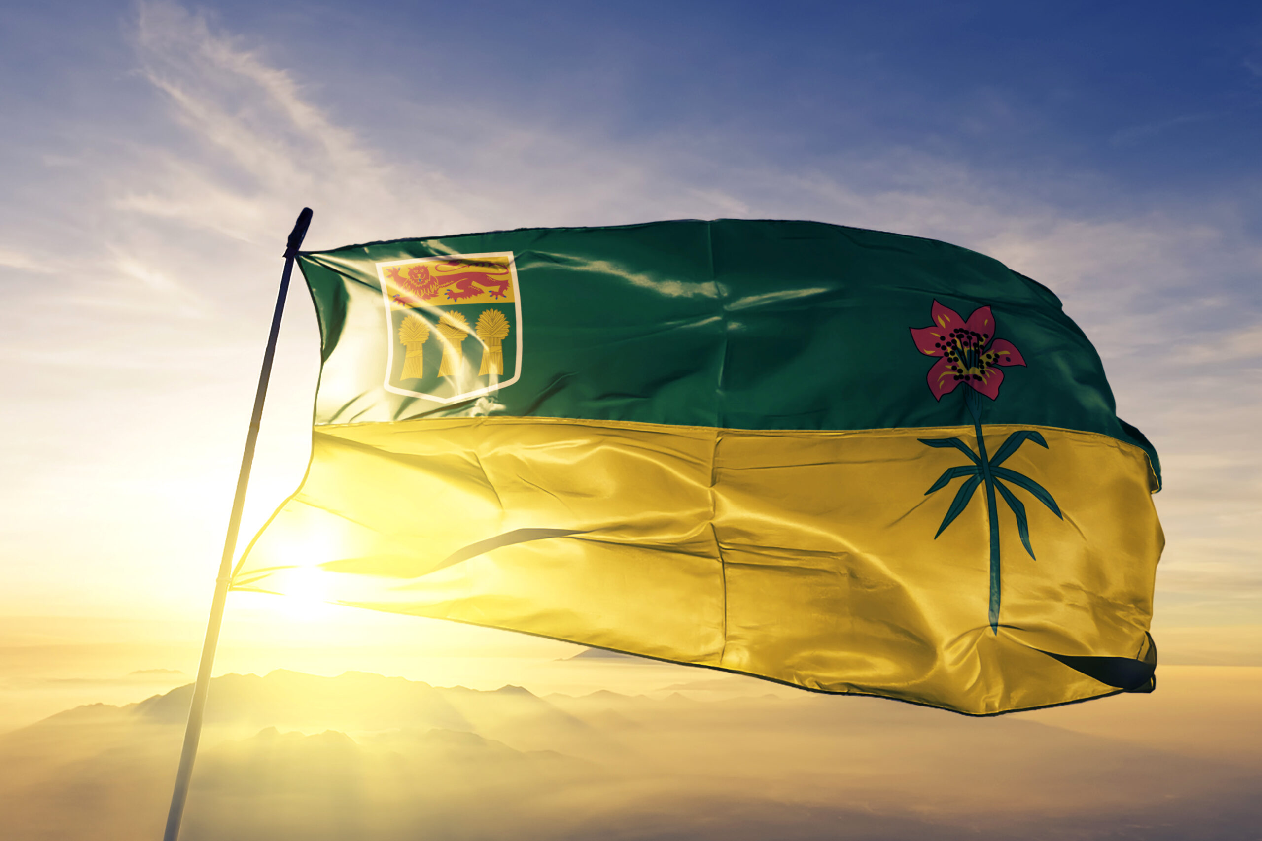 Saskatchewan province of Canada flag on flagpole textile cloth fabric waving on the top sunrise mist fog