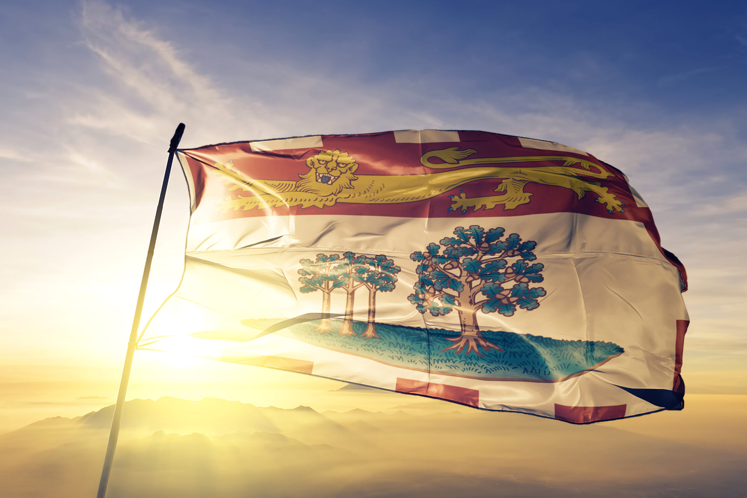 Prince Edward Island province of Canada flag on flagpole textile cloth fabric waving on the top sunrise mist fog